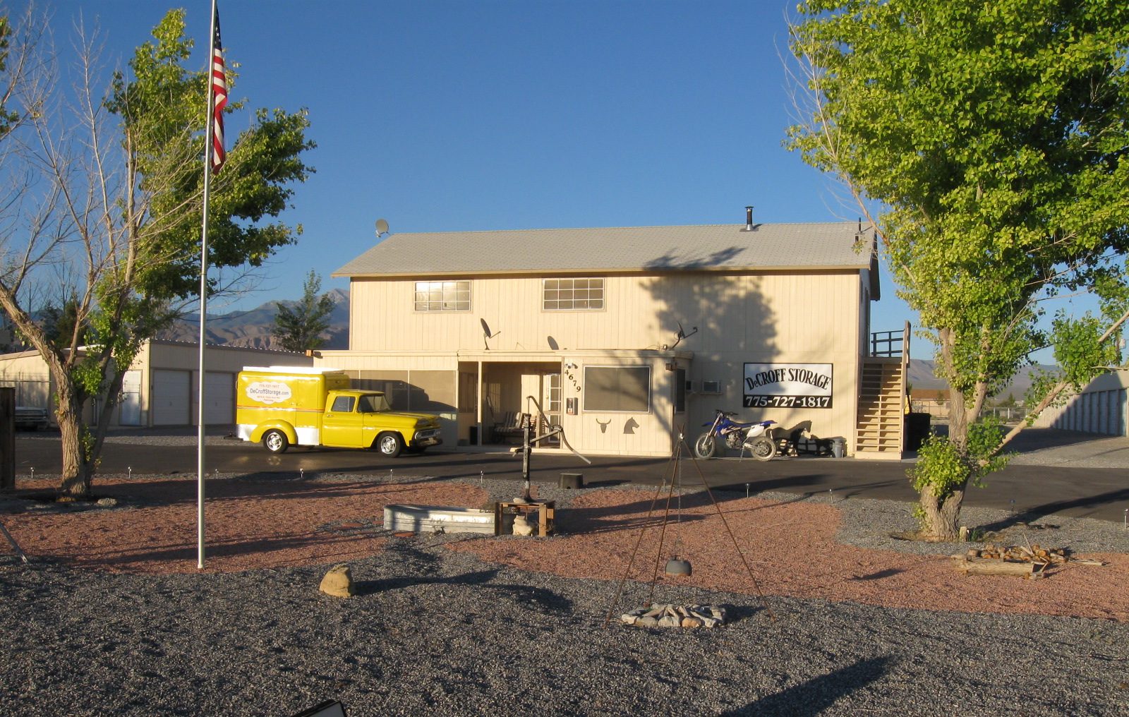 The Decroff Storage office building with its sign, an American flag on the pole and the yellow delivery truck parked out front.